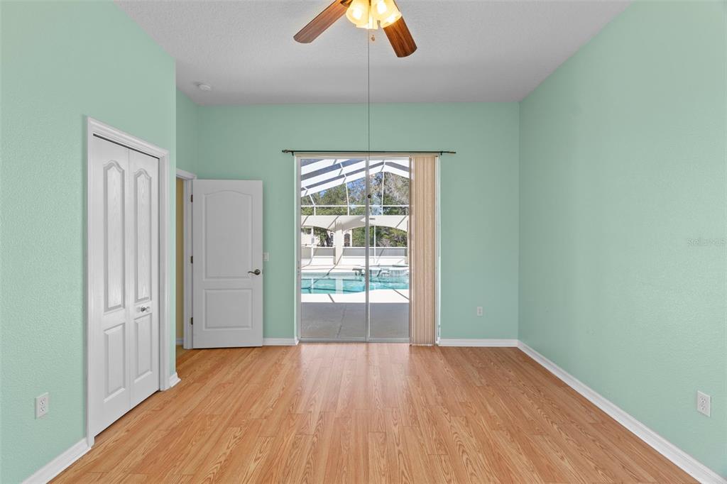 10130 Lazy Days Court Weeki Wachee, FL 34613 - Photo 43 of 85 an empty room with wooden floor chandelier fan and windows