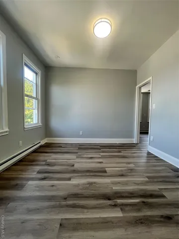 a view of empty room with window and wooden floor