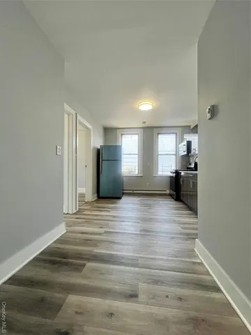 a view of kitchen and empty room with wooden floor