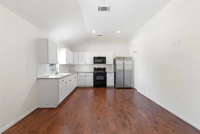 a kitchen with a refrigerator and white cabinets