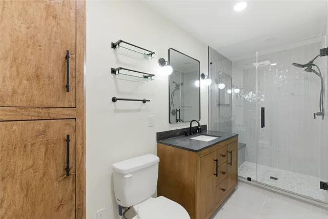 a bathroom with a granite countertop sink toilet a mirror and shower