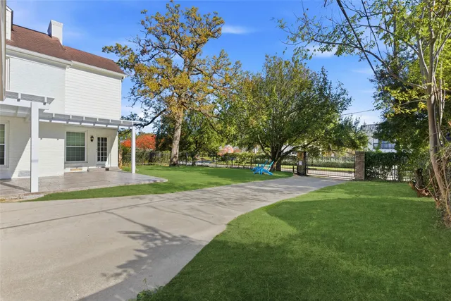 a view of a white house with a big yard and large trees
