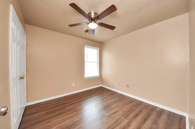 a view of an empty room with wooden floor and a window