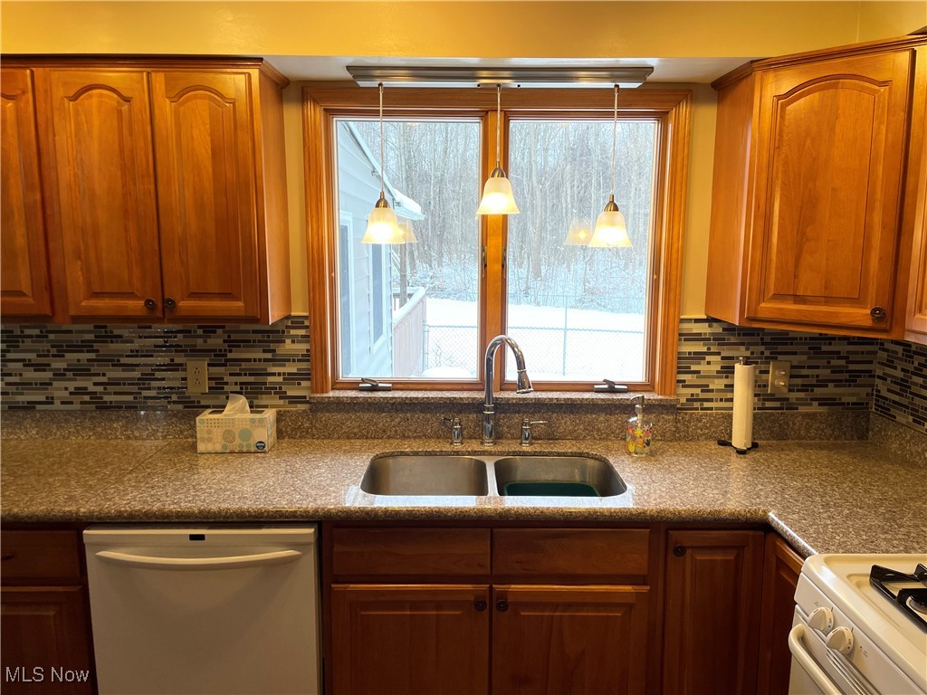 1381 Robb Road Conneaut, OH 44030 - Photo 14 of 50 Kitchen featuring white appliances, decorative backsplash, brown cabinetry, and decorative light fixtures
