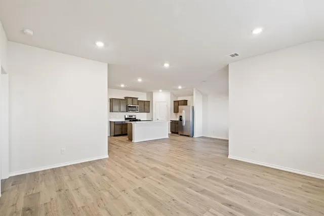a view of kitchen with kitchen island stainless steel appliances cabinets and wooden floor
