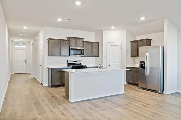 a white kitchen with wooden floor and stainless steel appliances