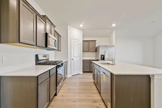a kitchen with stainless steel appliances a sink stove and wooden floor