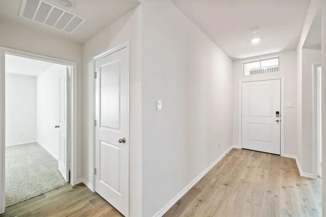 a view of a hallway with wooden floor and closet area