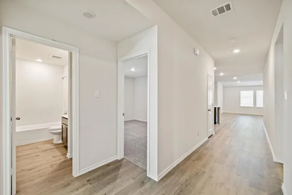 a view of a hallway with wooden floor and a bathroom