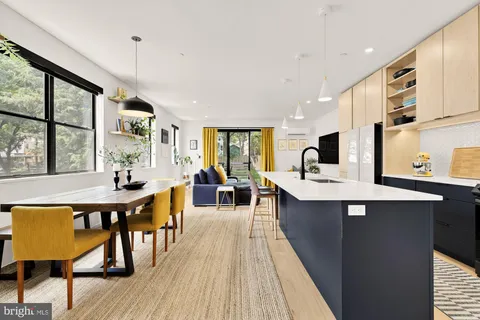 a large kitchen with kitchen island a large island in the center a sink a window cabinets and stainless steel appliances