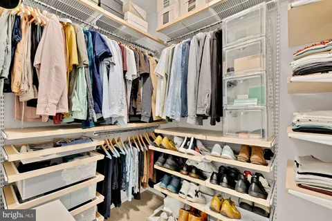 a view of walk in closet with clothes and shoes