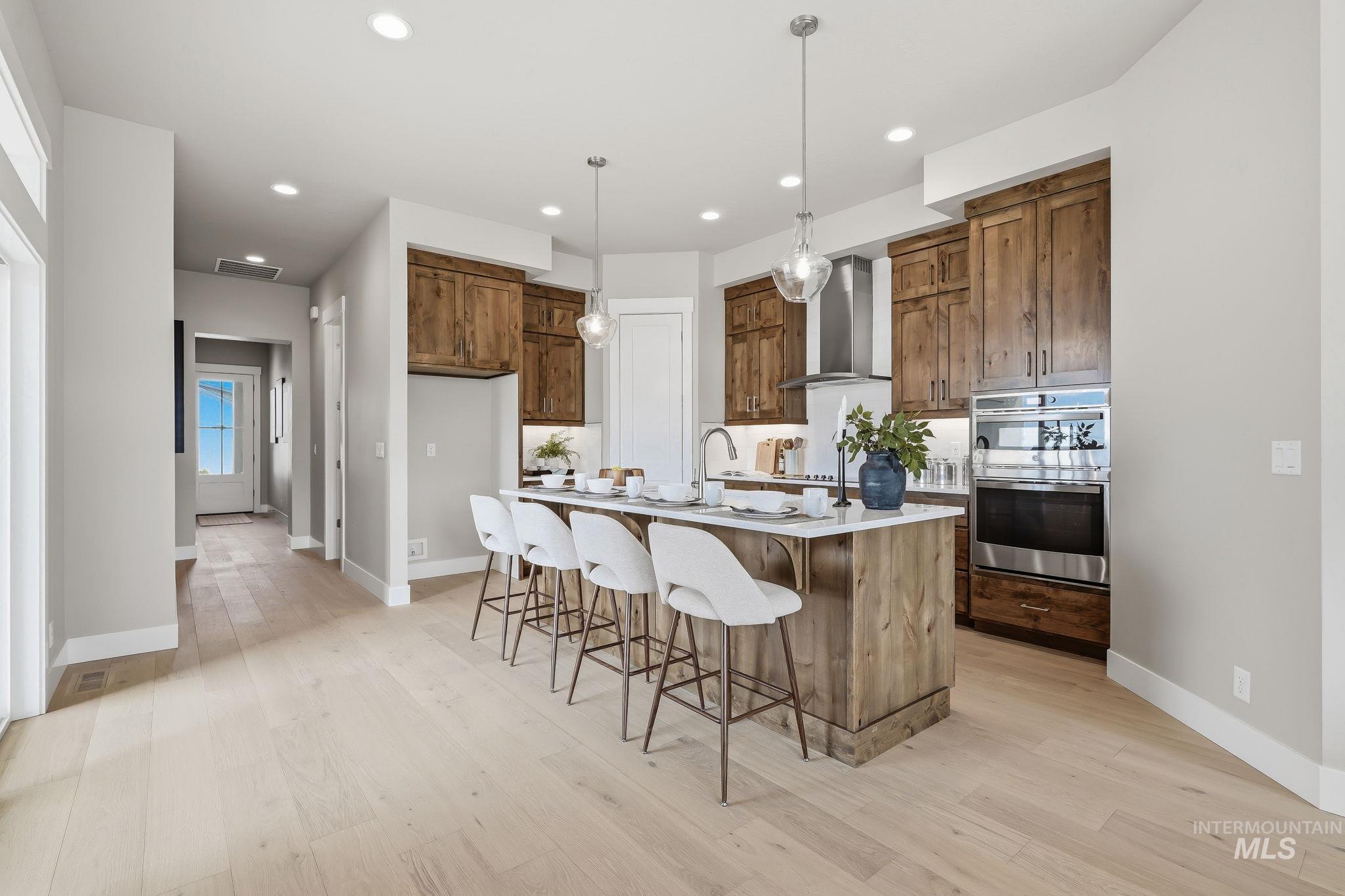470 South Radiator Way Boise, ID 83716 - Photo 33 of 50 Gourmet kitchen featuring a substantial central island with seating, natural wood cabinetry, stainless steel appliances, and light wood-finish flooring