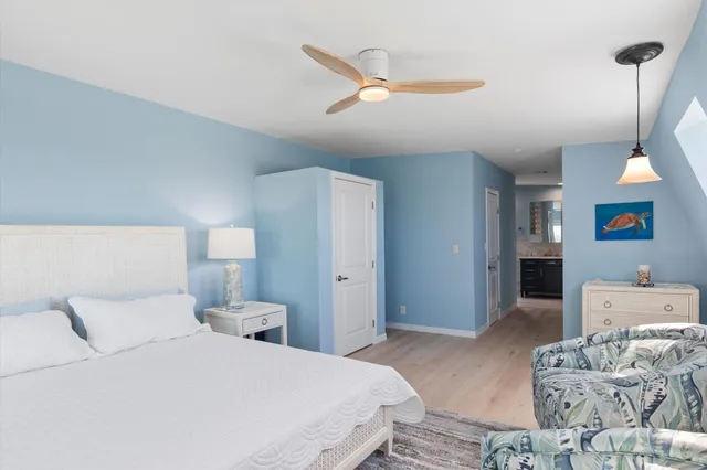 a view of a balcony with dining table and chairs under an umbrella with a barbeque grill and wooden floor