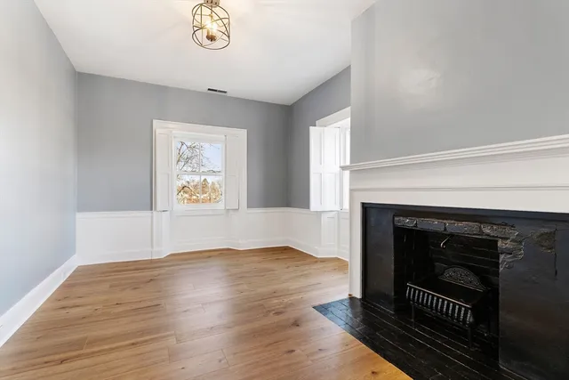 an empty room with wooden floor a fireplace and windows