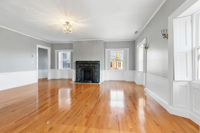 an empty room with wooden floor fireplace and windows