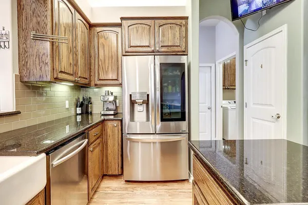 a kitchen with stainless steel appliances granite countertop a refrigerator a sink and white cabinets
