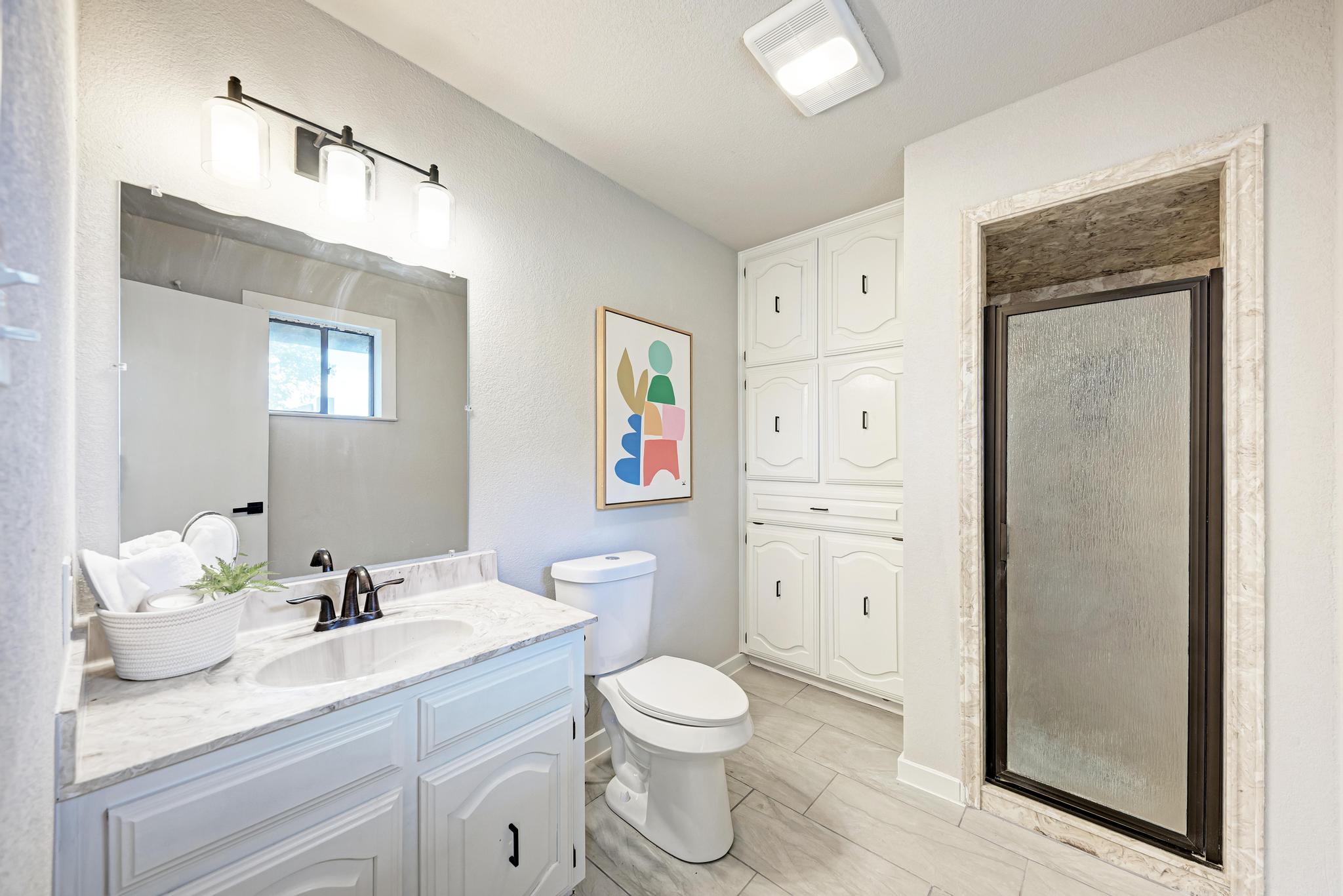 2365 Hackberry Road Salado, TX 76571 - Photo 25 of 40 a bathroom with a granite countertop sink toilet a large mirror a vanity and shower