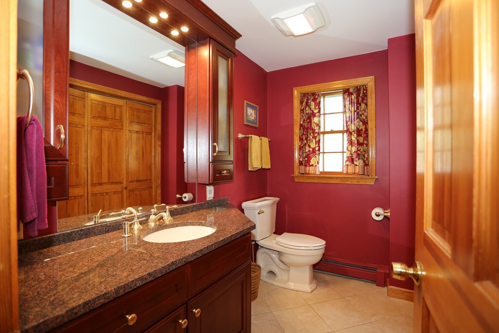 28 Middle Road Sudbury, MA 01776 - Photo 17 of 24 a bathroom with a granite countertop toilet a sink a mirror and a window