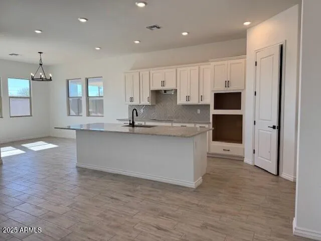 a kitchen with stainless steel appliances granite countertop a refrigerator a sink dishwasher and white cabinets with wooden floor