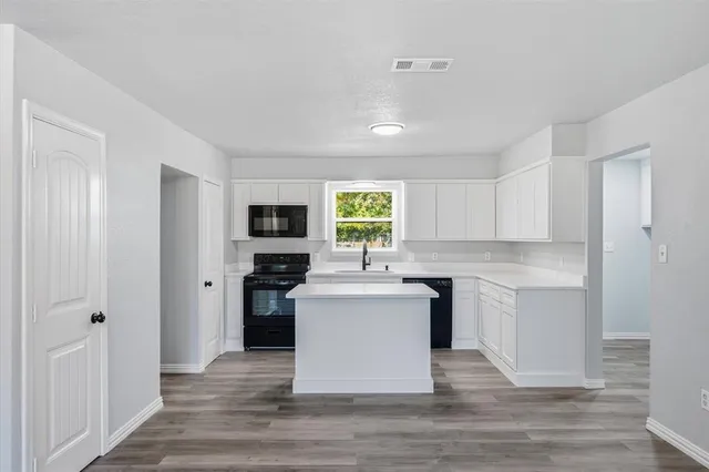a kitchen with stainless steel appliances kitchen island granite countertop a stove top oven and refrigerator