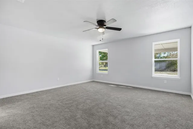 an empty room with windows and fan