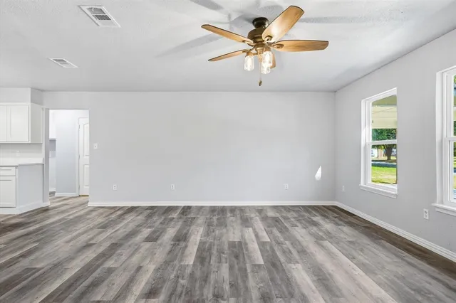an empty room with a window and a ceiling fan