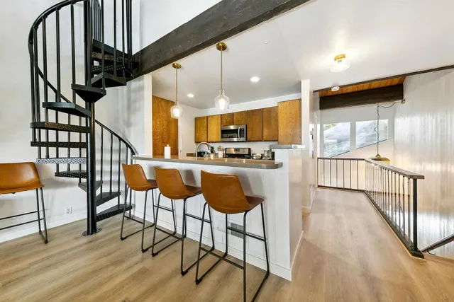 a kitchen with stainless steel appliances kitchen island granite countertop wooden floor a dining table and chairs