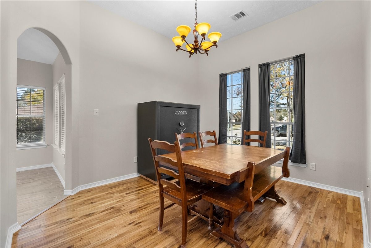8102 Pinewood Park Humble, TX 77346 - Photo 6 of 37 a dining room with wooden floor a chandelier a wooden table and chairs