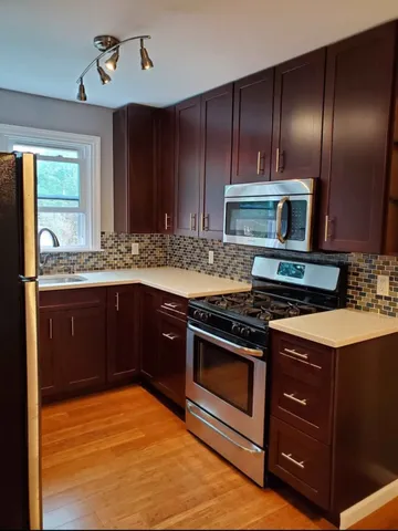 a kitchen with stainless steel appliances granite countertop wooden cabinets and a stove top oven