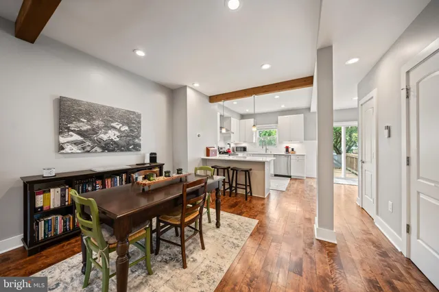 a dining hall with stainless steel appliances a dining table wooden floor and a rug