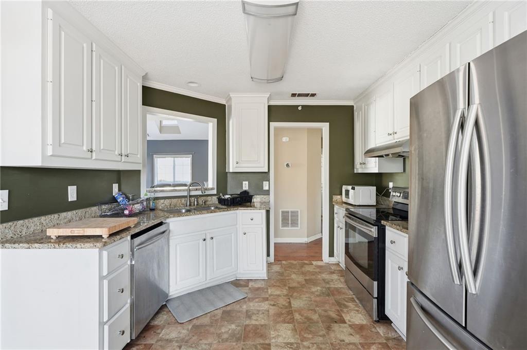 355 Radcliffe Trace Covington, GA 30016 - Photo 7 of 28 a kitchen with white cabinets and stainless steel appliances