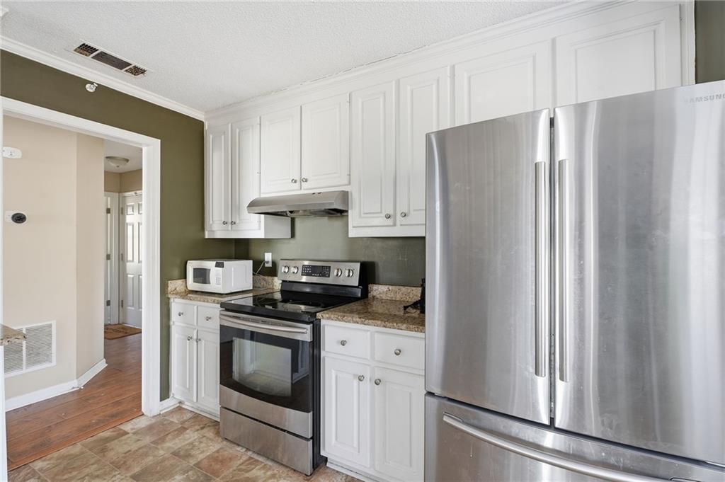 355 Radcliffe Trace Covington, GA 30016 - Photo 9 of 28 a kitchen with stainless steel appliances white cabinets and a refrigerator
