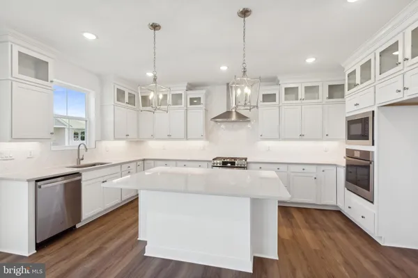 a large kitchen with white cabinets and wooden floor