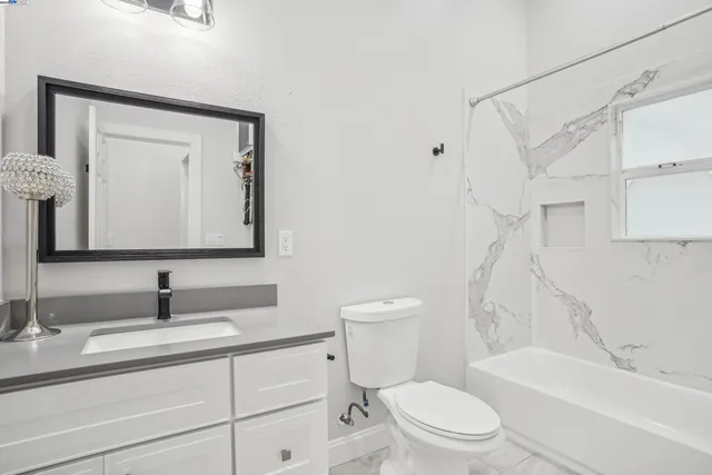a bathroom with a toilet a sink a tub and mirror