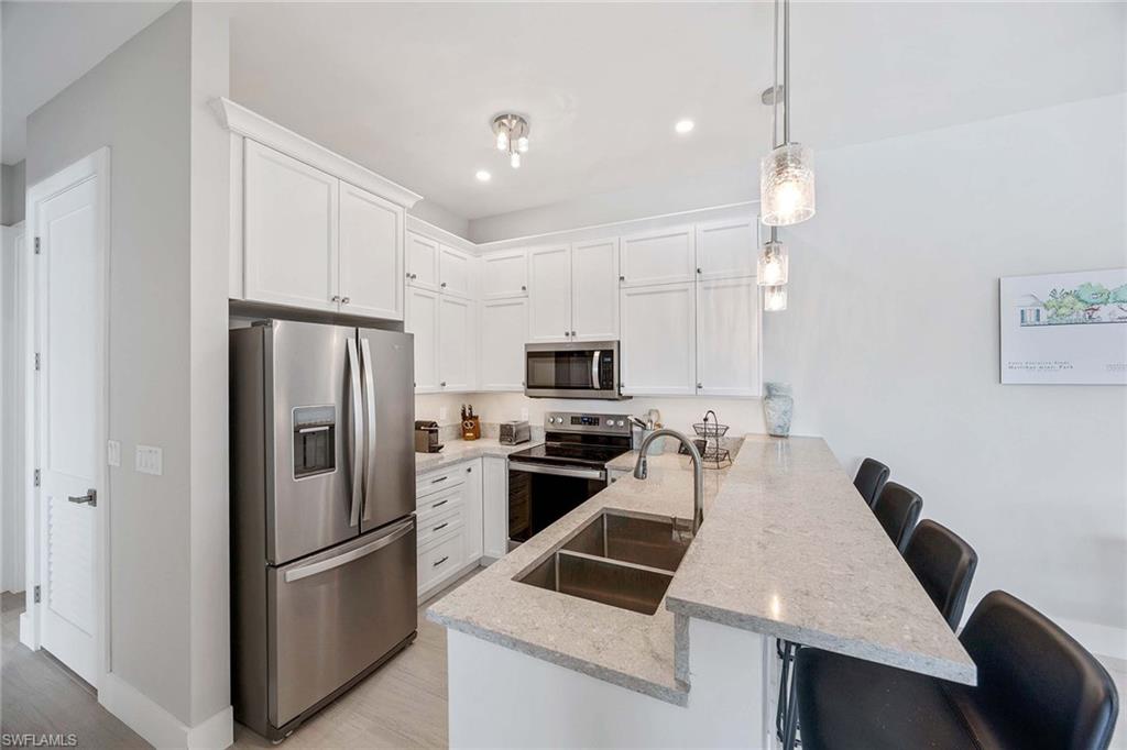 1395 Curlew Avenue, Unit 43 Naples, FL 34102 - Photo 6 of 24 a kitchen that has a refrigerator a stove and white cabinets with wooden floor
