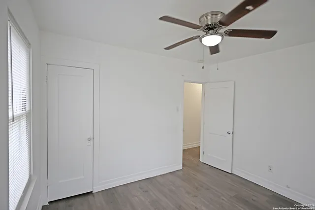 an empty room with wooden floor fan and windows