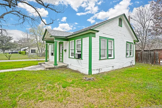a view of a house with a yard and a large tree