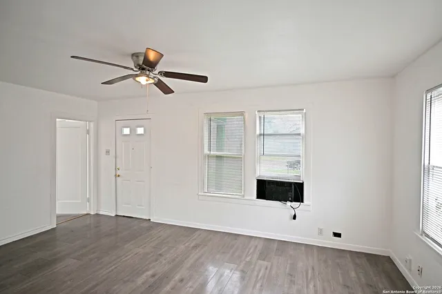 a view of an empty room with a window and wooden floor