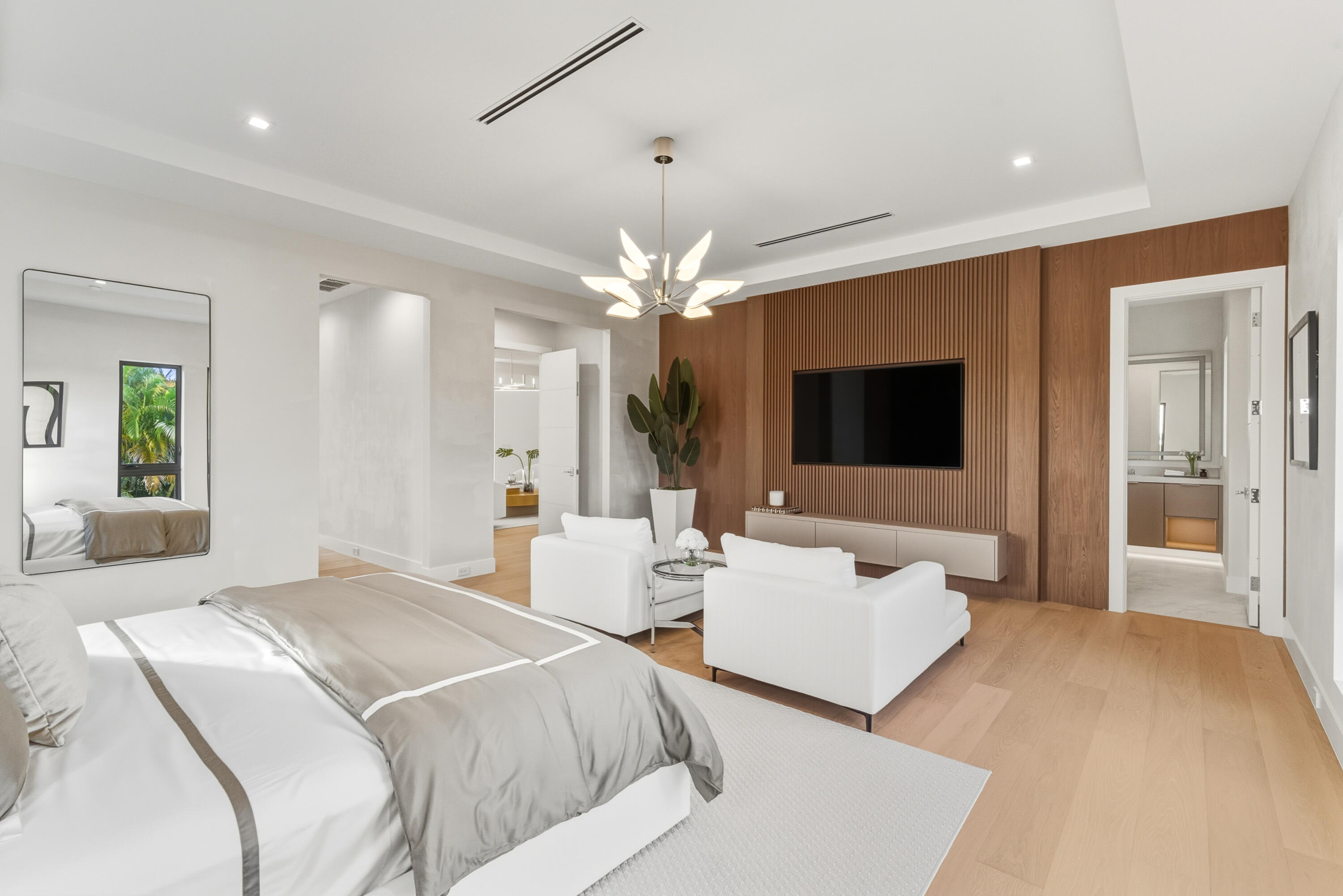 450 Northeast Spanish Court Boca Raton, FL 33432 - Photo 18 of 32 a spacious bedroom with a large bed a flat screen tv and a chandelier