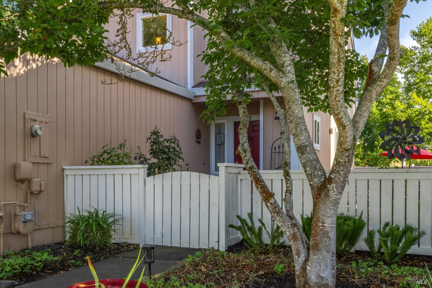 a view of a house with wooden fence and potted plants