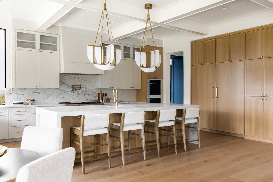 9117 Brookhurst Cove Austin, TX 78733 - Photo 10 of 40 a kitchen with stainless steel appliances granite countertop a sink a stove a dining table and chairs with wooden floor