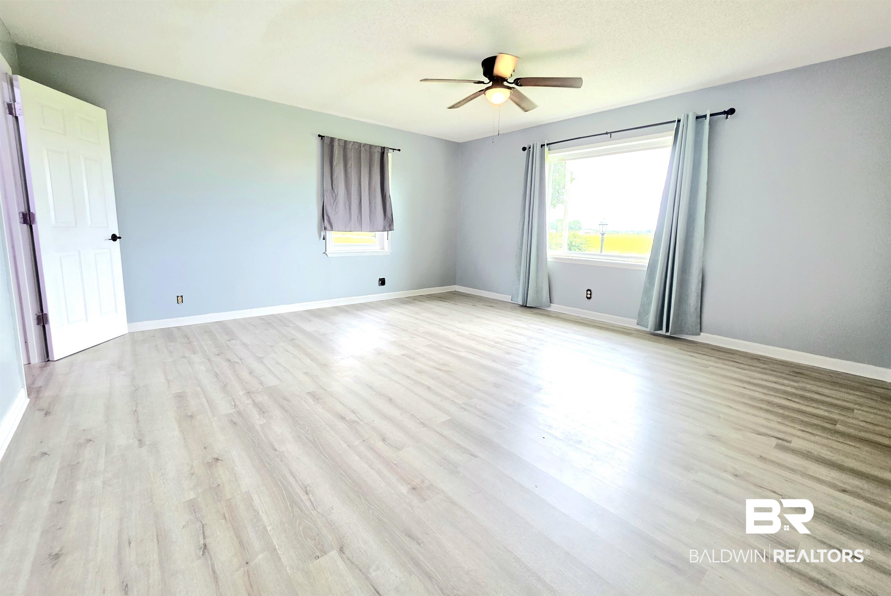 558 Stanton Road Atmore, AL 36502 - Photo 7 of 29 Spacious room featuring light wood-finish flooring, light blue wall paint, and white trim