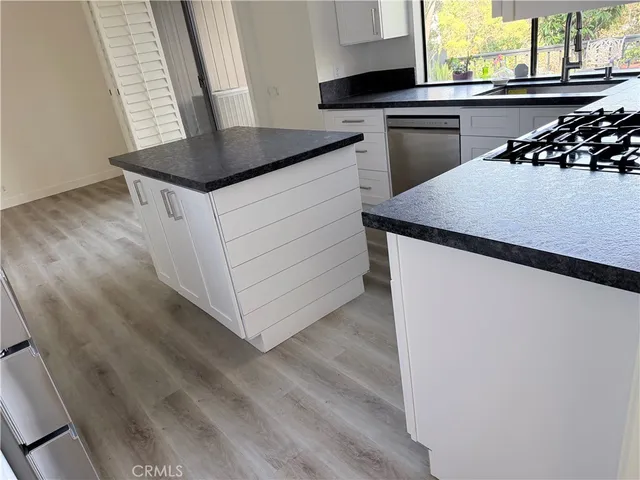 a kitchen with a sink a stove and wooden floor