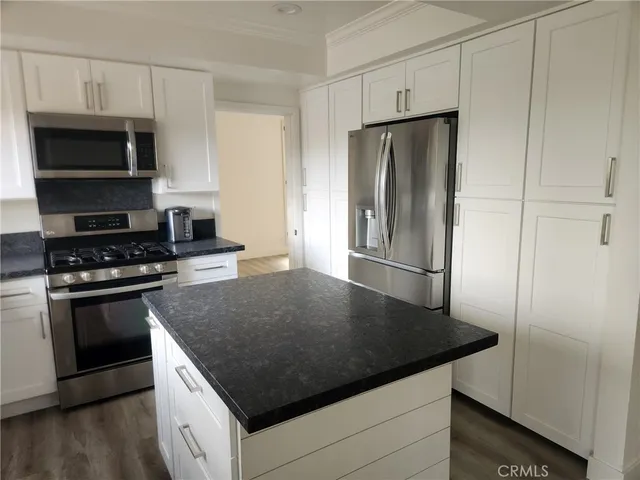 a kitchen with granite countertop a refrigerator and a stove top oven