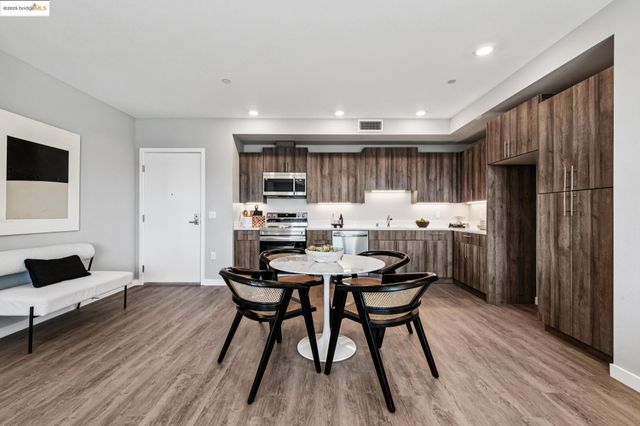 a kitchen with stainless steel appliances kitchen island granite countertop a refrigerator a stove a sink dishwasher and white cabinets with wooden floor