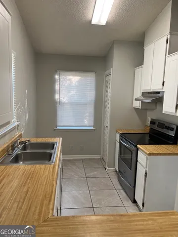 a kitchen with granite countertop a stove a sink and a refrigerator
