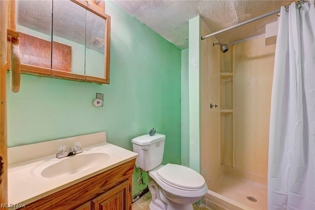 15512 Greenway Road Cleveland, OH 44111 - Photo 14 of 18 Bathroom with toilet, vanity, tile floors, a textured ceiling, and walk in shower