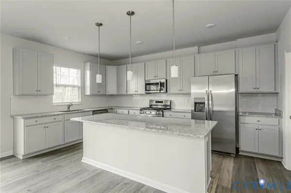 a kitchen with granite countertop cabinets stainless steel appliances a sink and a wooden floor