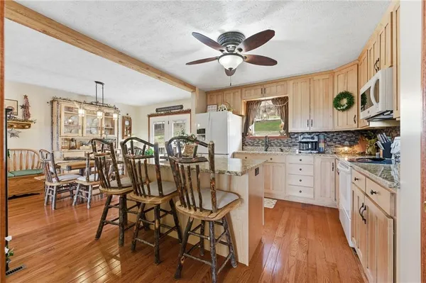 a kitchen with stainless steel appliances a dining table chairs stove and cabinets