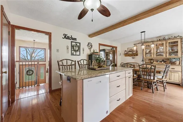 a kitchen with stainless steel appliances kitchen island granite countertop a table chairs cabinets and wooden floor